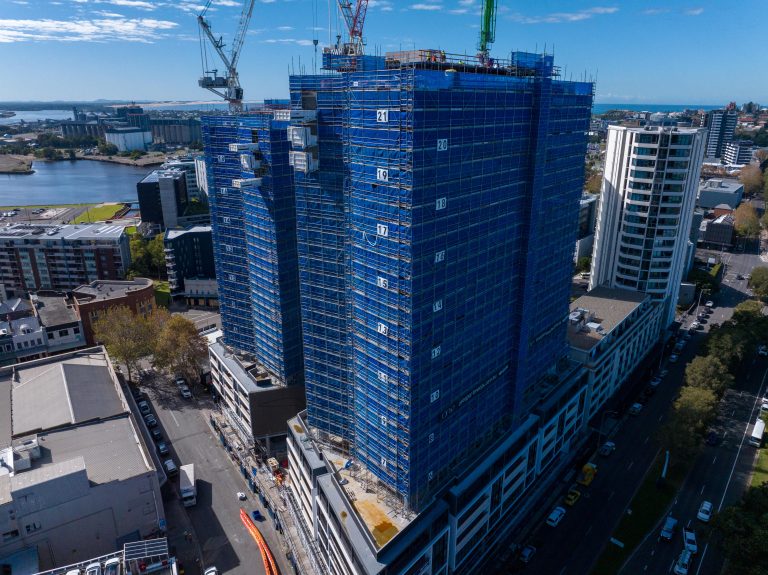 Commercial building is completely covered in a dense metal scaffold and a blue protective mesh.